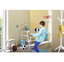 Kind spielt im hellen Kinderzimmer mit Schreibtisch, Stuhl, Lampe, Basketballkorb und Fußball