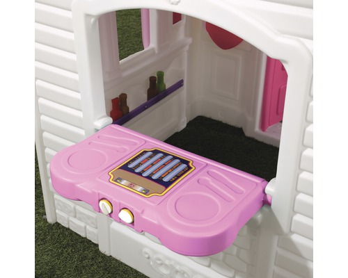 Detailansicht eines Spielhauses mit rosa Tresen und kleinen Regalen im Inneren
