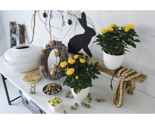 Festliche Osterdekoration mit Rosen, Ostereiern und Osterhasen auf einem Tisch.