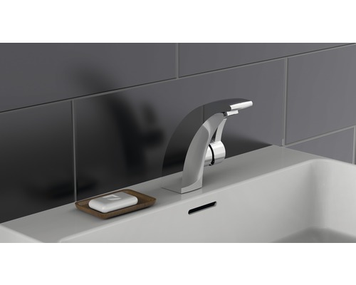 Auf einem Waschbecken befindet sich eine Armatur und eine Seife in einer Schale.