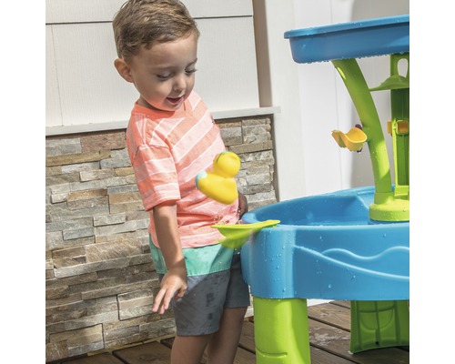 Ein Kind spielt mit einem blauen und grünen Wasserwerkzeug im Freien.