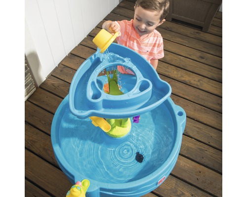 Junge spielt mit einem blauen Wasserspieltisch im Freien