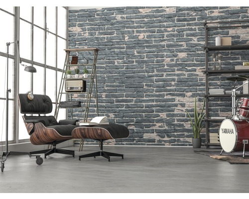 Wohnzimmer mit Sessel, Hocker, Regal und Ziegelwand