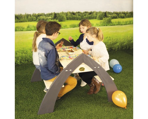 Kinder sitzen an einem Kinderspieltisch im Freien