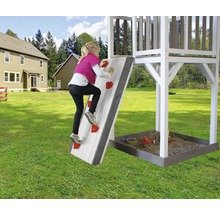 Kind klettert an einer Kletterwand eines Spielhauses im Garten.