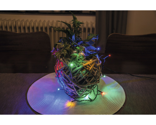 Dekorative Pflanzenarrangement mit Lichtern in einem geflochtenen Korb auf einem Tisch