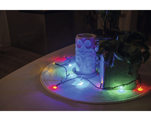 Dekoration mit Kerze, Zimmerpflanzen und Lichterkette auf einem Tisch