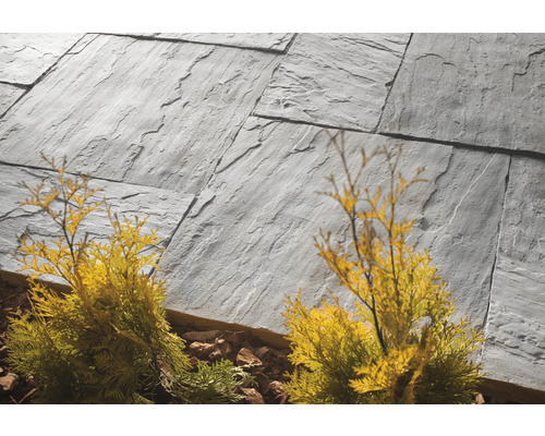 Pflastersteine aus Naturstein mit Pflanzen im Garten