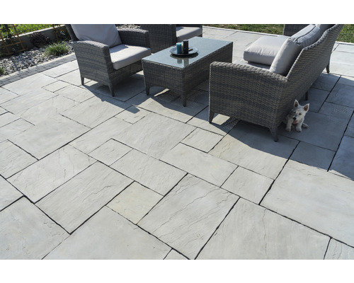 Terrasse mit hellen Terrassenplatten und Gartenmöbeln