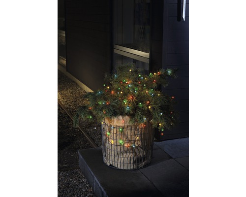 Dekorativer Weihnachtsbaum mit Lichtern in einem Jutesack und Drahtkorb im Außenbereich.