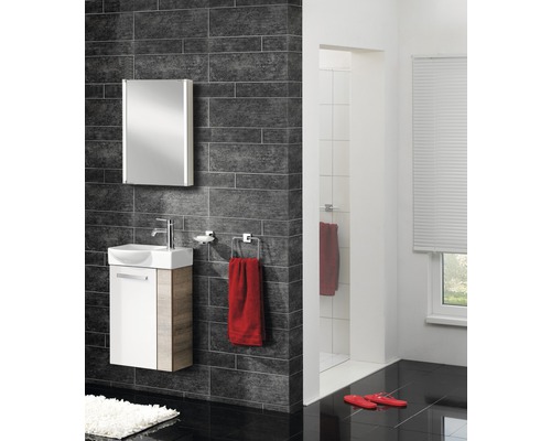 Badezimmer mit Waschtisch, Spiegelschrank, Handtuch und dunklen Fliesen