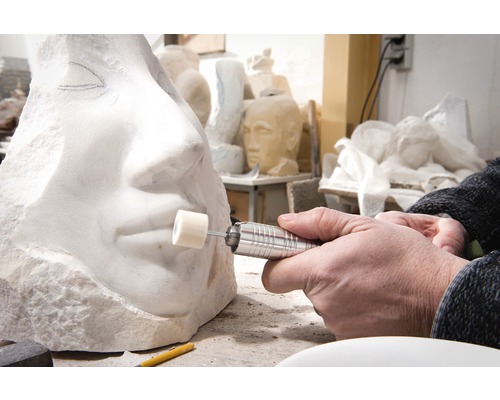 Nahaufnahme einer Person, die eine Steinskulptur mit einem Rotationswerkzeug bearbeitet
