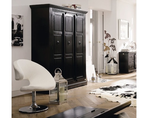 Einrichtungsszene mit einem schwarzen Kleiderschrank, einem weißen Sessel und dekorativen Laternen in einem hellen Raum.