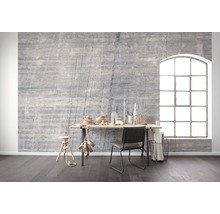 Wohnraum mit grauer Betonwand, Schreibtisch, Stuhl und großem Fenster für eine helle und moderne Atmosphäre.