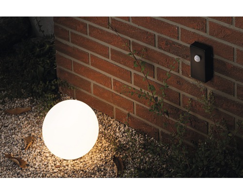 Szene mit einer runden Außenleuchte und einem Bewegungsmelder an einer Ziegelwand