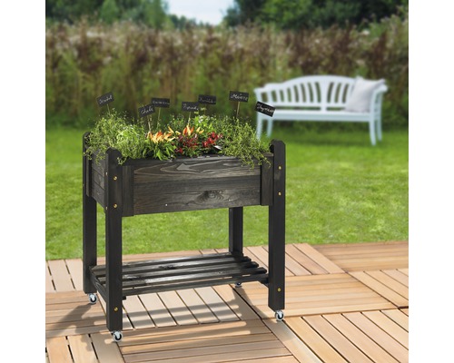 Hochbeet aus Holz mit Kräutern und Rollen im Garten