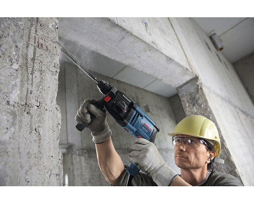 Ein Mann bohrt mit einem Bohrhammer in eine Betonwand