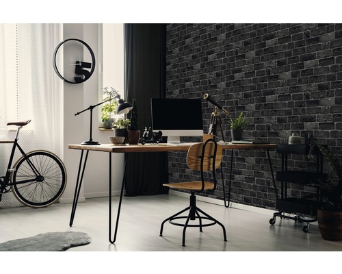 Arbeitszimmer mit Schreibtisch, Stuhl, Fahrrad und Backsteintapete