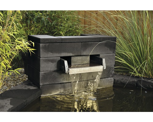 Gartenbrunnen aus Steinen mit Wasserfall in einem Teich