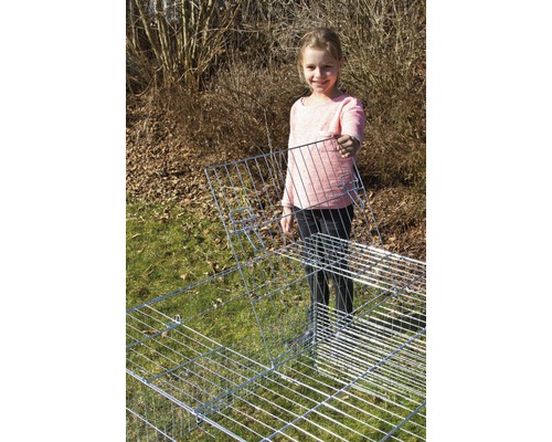 Mädchen hält ein Gitterelement eines Kleintiergeheges im Garten