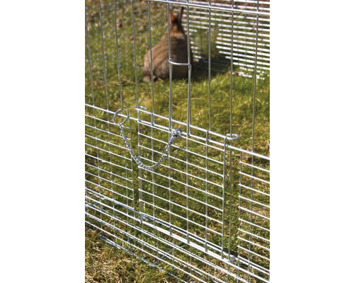 Nahaufnahme eines Metallzauns mit Verschluss und einem Kaninchen im Hintergrund