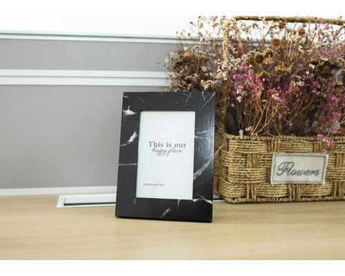 Schwarzer Bilderrahmen mit Marmoroptik neben einem Blumenkorb.