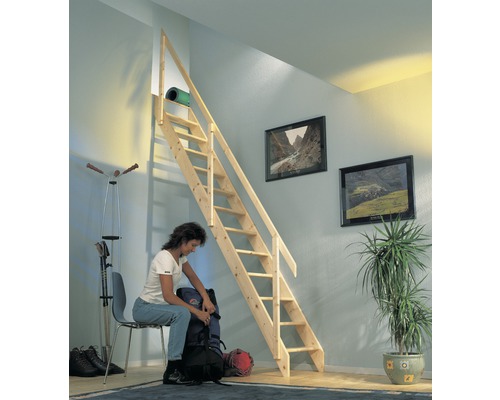 Raumszene mit Holztreppe zu einem Dachboden, eine Frau sitzt auf einem Stuhl und packt einen Rucksack