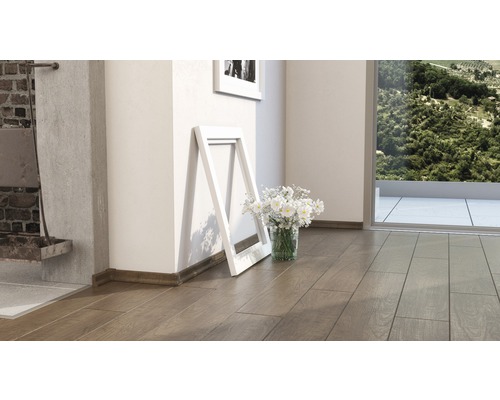 Innenraum mit Holzboden, weißem Bilderrahmen und Blumen in einer Vase