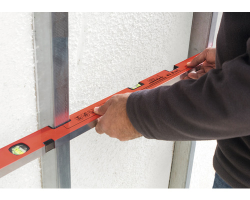 Handwerker mit Wasserwaage an Metallprofil