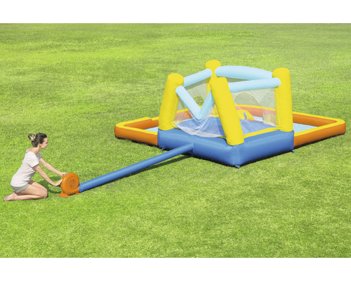 Aufblasbare Hüpfburg mit Pool im Garten mit Frau beim Aufpumpen.