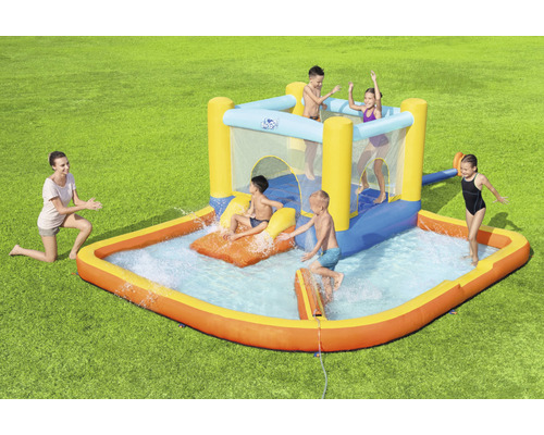 Aufblasbare Hüpfburg mit Wasserrutsche und Planschbecken im Garten mit spielenden Kindern
