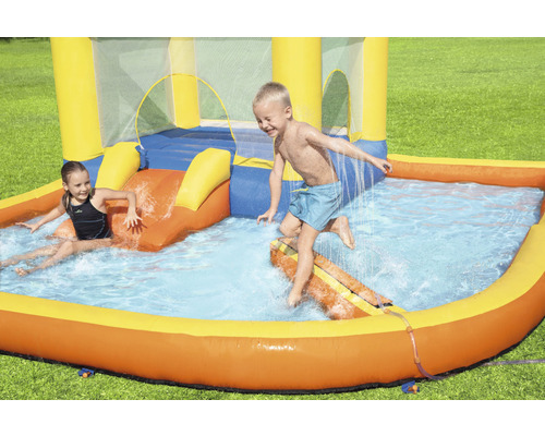 Aufblasbare Hüpfburg mit Pool und spielenden Kindern im Garten.