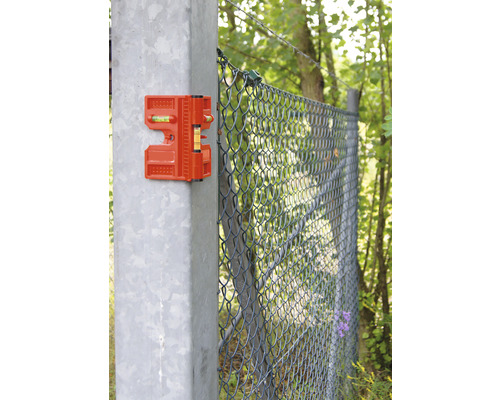 Orangefarbene Zaunbaurichtwaage an einem Zaunpfosten zur Ausrichtung beim Zaunbau