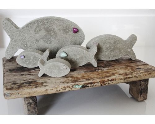 Dekorative Fischfiguren aus Beton auf Holzpodest