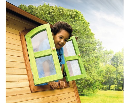 Junge schaut aus Fenster eines Holzspielhauses