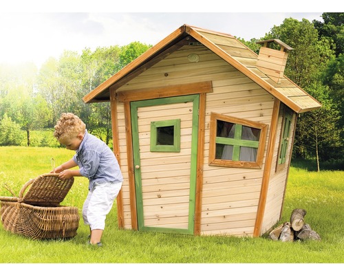 Kind mit Picknickkorb vor einem Holzspielhaus im Garten.
