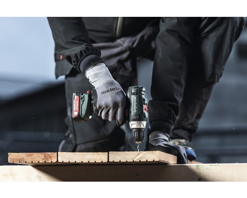 Eine Person bohrt mit einem Metabo Akku-Bohrschrauber ein Holzbrett.