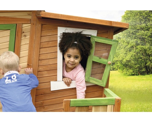 Kinder spielen in einem Holzspielhaus mit Fenster.