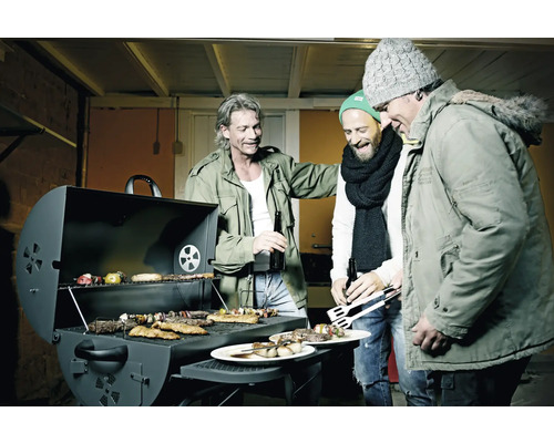 Drei Männer stehen um einen Grill mit Fleisch, Gemüse und Spießen.