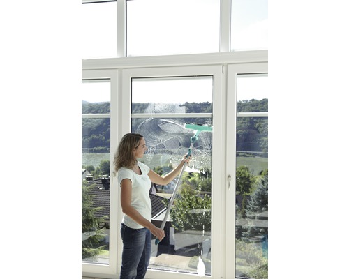 Frau putzt Fenster mit Fensterwischer
