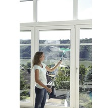 Eine Frau putzt ein Fenster mit einem Fensterwischer.