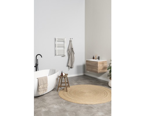 Helles Badezimmer mit freistehender Badewanne, Waschtischunterschrank, Handtuchwärmer und rundem Teppich