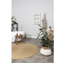 Badezimmer mit Badewanne, Handtuchwärmer, rundem Teppich und Zimmerpflanzen