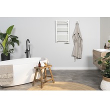 Modernes Badezimmer mit Badewanne, Waschtisch, Handtuchwärmer und Dekorationen.