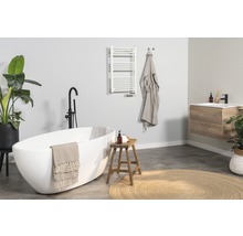 Helles Badezimmer mit Badewanne, Waschtisch, Handtuchwärmer und Dekorationen für eine freundliche Atmosphäre.