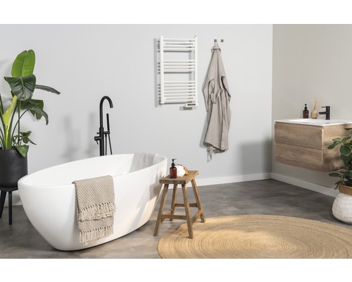 Helles Badezimmer mit Badewanne, Waschtisch, Handtuchwärmer und Dekorationen für eine freundliche Atmosphäre.