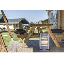 Szene mit einem Holz-Picknicktisch, Kissen und einem Heizgerät vor Zelten