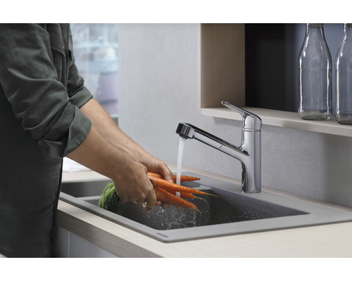 Person wäscht Karotten unter einer Küchenarmatur