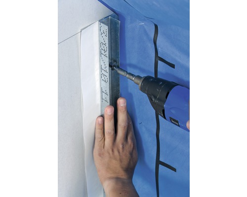 Eine Person befestigt mit einem Akkuschrauber eine Metallschiene an einer Wand.