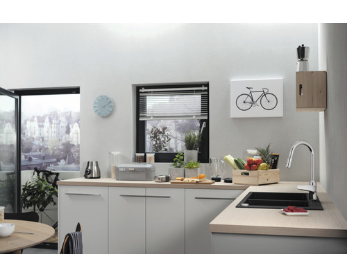 Helle Küche mit Spüle, Armatur und Küchenutensilien auf der Arbeitsplatte.